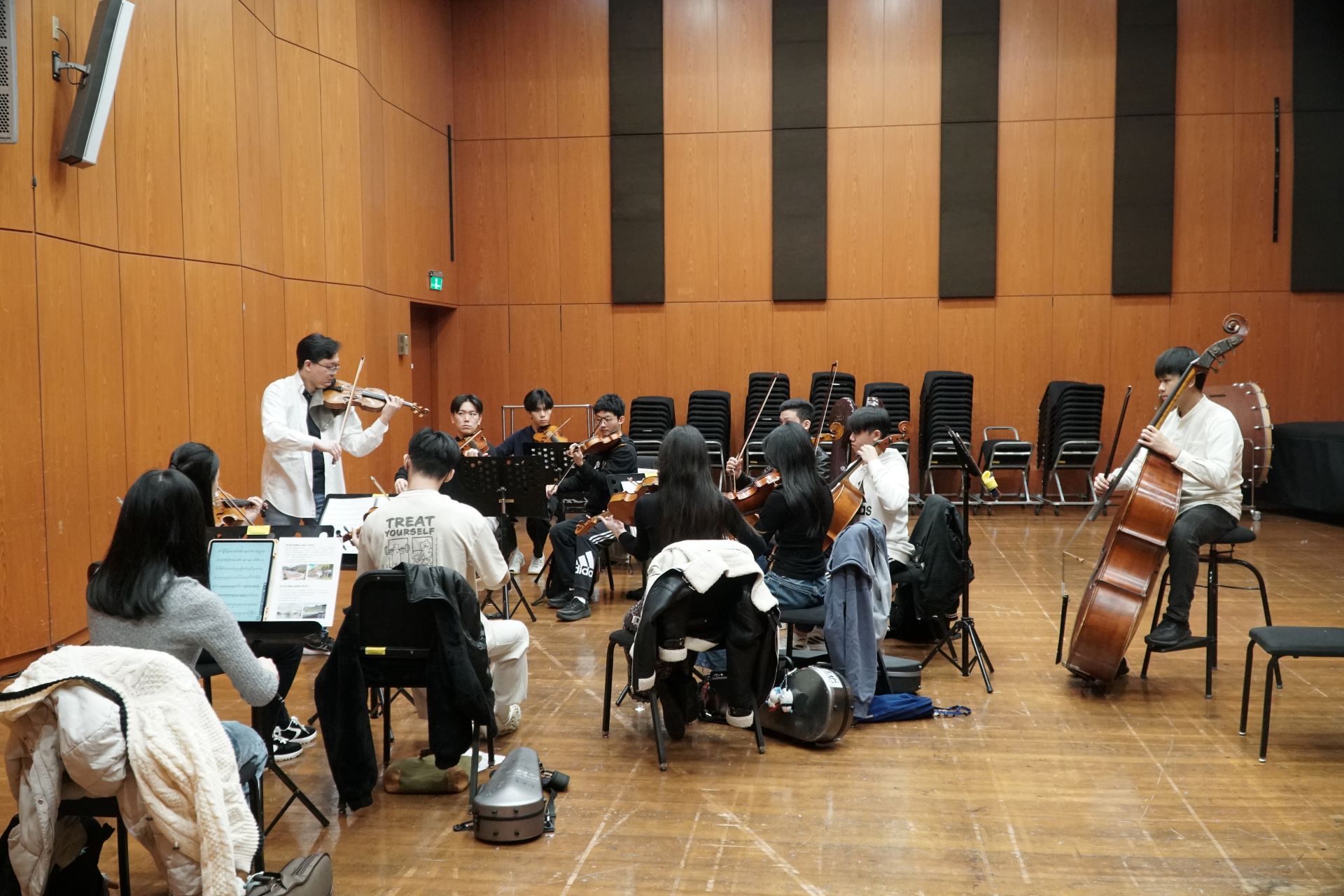 The teacher and students holding the violins watched the score and discussed.